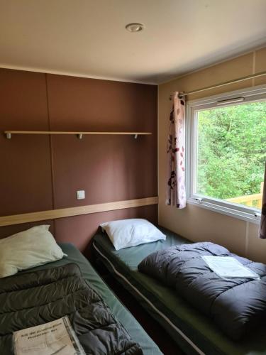 two beds in a room with a window at Mobil Home Camiers in Camiers