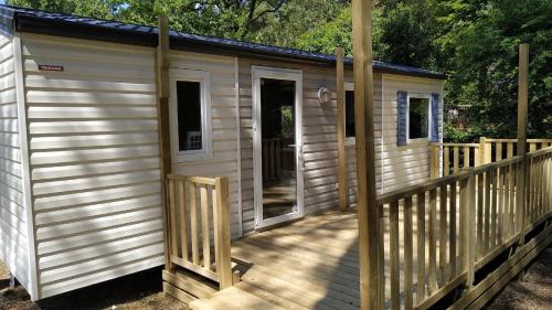 a large wooden cabin with a wooden deck at Mobil Home Camiers in Camiers