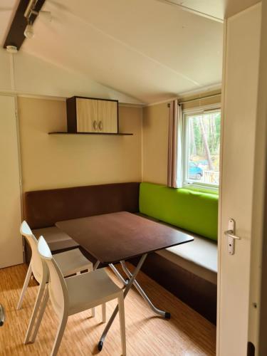 a small room with a table and a green couch at Mobil Home Camiers in Camiers