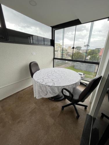 stół i krzesła w pokoju z oknami w obiekcie Talli Hotel w mieście Kurytyba
