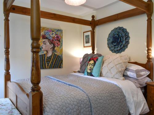 a bedroom with a canopy bed with a painting on the wall at Meadow View Cottage - Uk33302 in Middleton