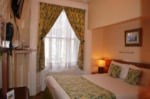 a hotel room with a bed and a window at Falcon Hotel in London