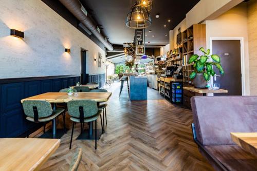a restaurant with wooden tables and green chairs at Hotel Inn Naeldwyk-Torenburg in Naaldwijk