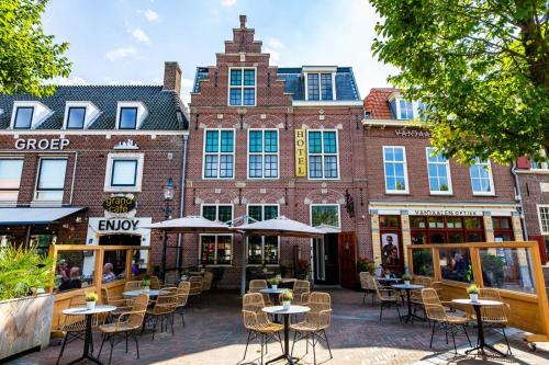 a building with tables and chairs in front of it at Hotel Inn Naeldwyk-Torenburg in Naaldwijk