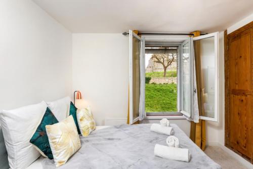 une chambre avec un lit avec une fenêtre et des serviettes dans l'établissement Le Pied à Terre de la Cité - Parking au Pied de la Cité, à Carcassonne
