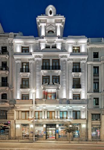 a large white building with a clock tower at Boutique Hotel H10 Villa de la Reina in Madrid