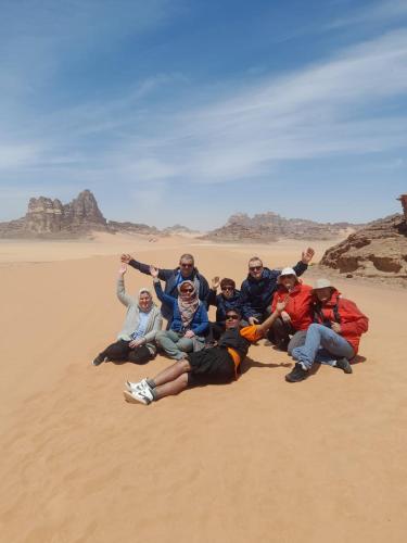 a group of people posing for a picture in the desert at Yara camp in Wadi Rum