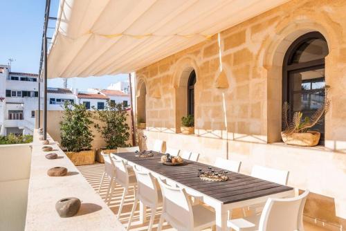 a patio with a wooden table and white chairs at Sa Capella : Ancienne chapelle rénovée avec piscine in Mahón