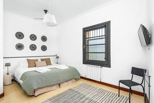 a bedroom with a bed and a chair and a window at Sa Capella : Ancienne chapelle rénovée avec piscine in Mahón