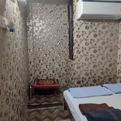 a room with two beds and a wall with wallpaper at Ira Homestay Mathura - Divine Spiritual Stay in Mathura