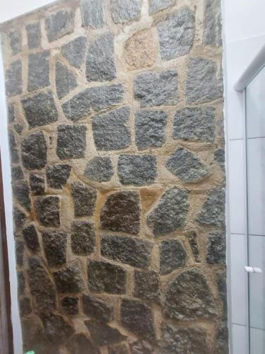 een stenen muur in een badkamer met douche bij Chalé do corisco in Paraty