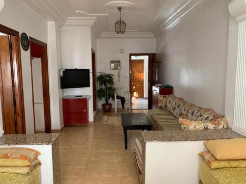a living room with couches and a flat screen tv at Superbe appartement chaleureux à 350m de la plage in M'diq