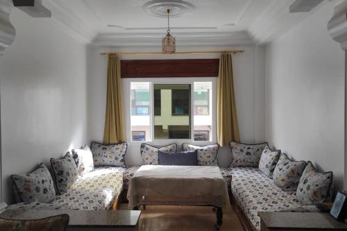 a living room with a couch and a bed at Superbe appartement chaleureux à 350m de la plage in M'diq