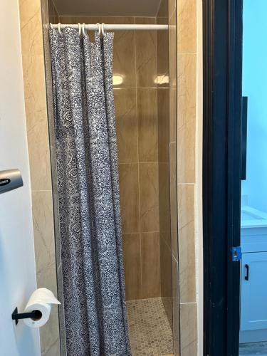 a glass shower with a shower curtain in a bathroom at The Palmerston in Toronto
