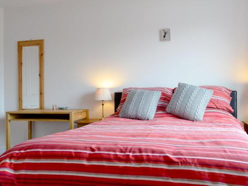 łóżko z czerwonym i białym kocem o paskach w obiekcie Ard Meanish w mieście Milovaig