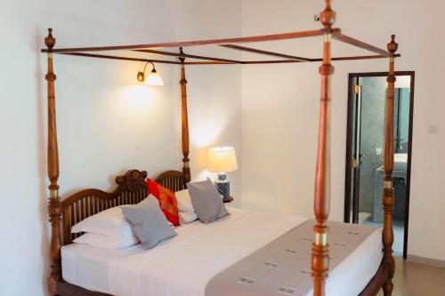 a bedroom with a canopy bed with white sheets and pillows at Coco Mantra Ilukwehera Estate 