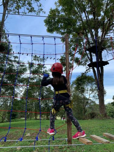 a young girl is climbing on a net at Bosque de Aventura & Glamping El Faro in La Mesa