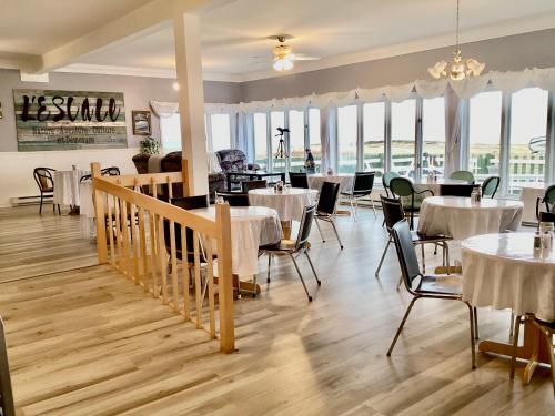 a dining room with tables and chairs and windows at L`Escale Lam-Air in Rivière-au-Tonnerre