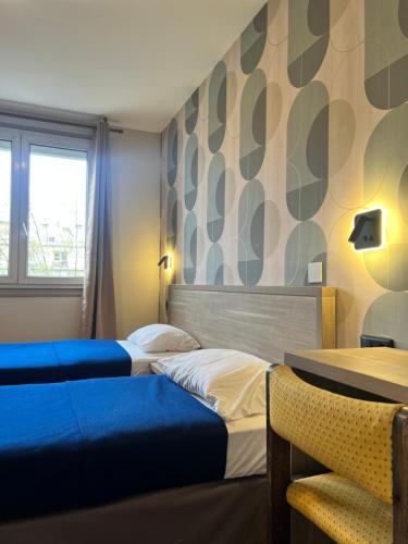 a hotel room with two beds and a window at Hotel Camelia in Boulogne-Billancourt