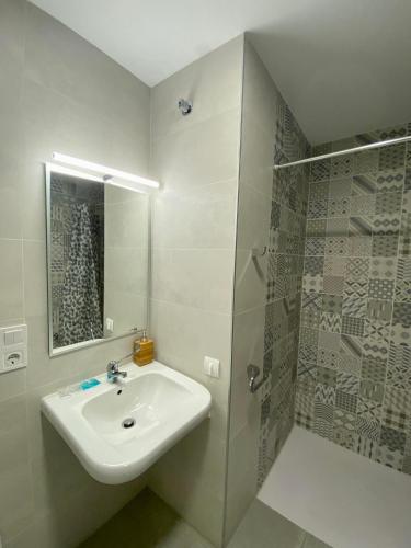 uma casa de banho branca com um lavatório e um chuveiro em El Mosaico Apartment em Valência