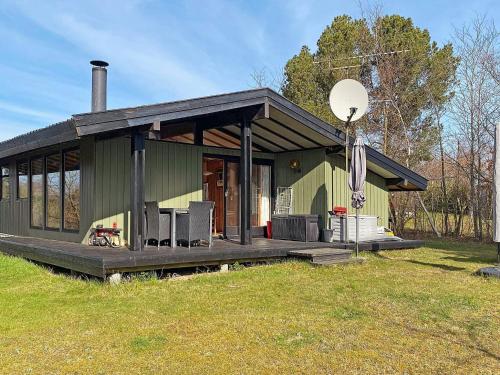 a green house with a porch and a grass field at 4 person holiday home in Skibby in Skibby