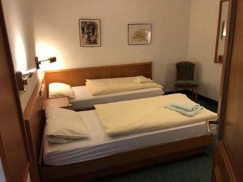 Duas camas num pequeno quarto com uma cadeira em Unterkunft zu Krone em Hofheim in Unterfranken