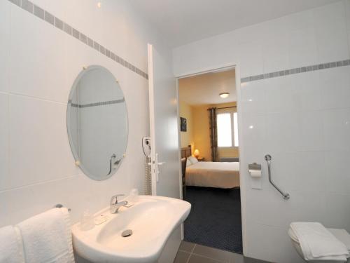 a white bathroom with a sink and a mirror at Hotel La Cabane in Belin-Beliet
