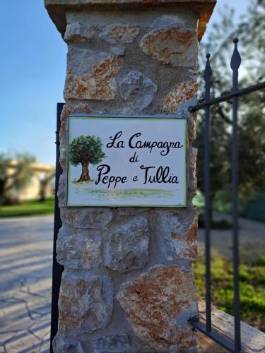 a sign on a stone wall with a tree on it at La Campagna di Peppe e Tullia in Formia