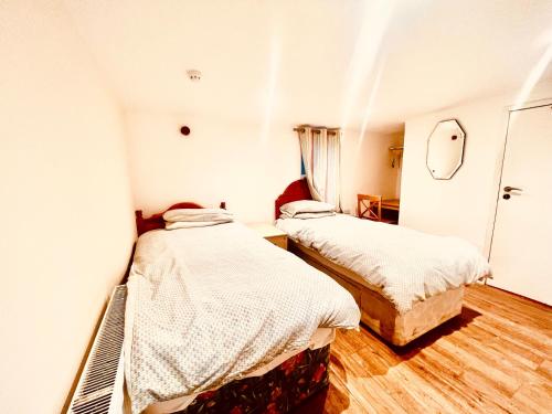 Duas camas num quarto com paredes brancas e pisos de madeira em White House Lodge em Cambridge