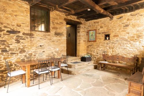 een kamer met een tafel en stoelen en een stenen muur bij CASA GRANDE VILAR in Vilar