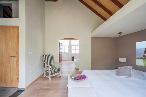 a bedroom with a large white bed and a chair at Villa L'Oasis in Oranjestad