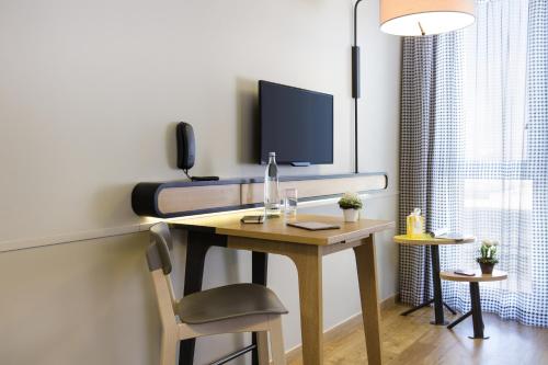 a room with a desk with a television on it at Aparthotel Adagio access München City Olympiapark in Munich