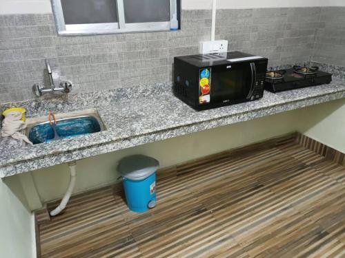 - un comptoir de cuisine avec évier et four micro-ondes dans l'établissement Primrose Homestay (A cozy 2 bedroom apartment), à Darjeeling