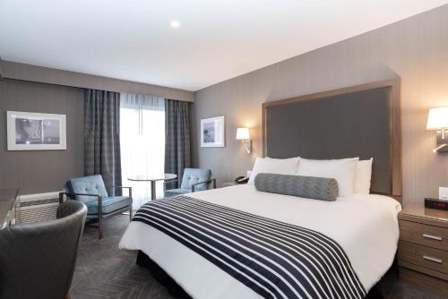 a hotel room with a large bed and chairs at Sandman Signature St. John's Hotel in St. John's