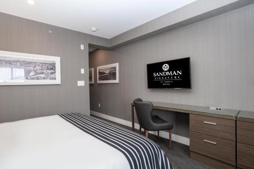 a bedroom with a bed and a desk with a monitor at Sandman Signature St. John's Hotel in St. John's