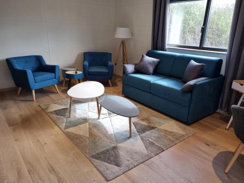 a living room with a blue couch and two chairs at Aérogites Chambley in Dommartin-la-Chapelle