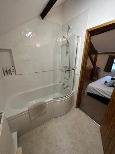 a bathroom with a tub with a shower and a bed at 36 Heritage House in Kington