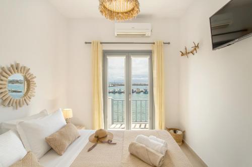 a bedroom with a large window with a view of the ocean at Yialos Rooms in Piso Livadi