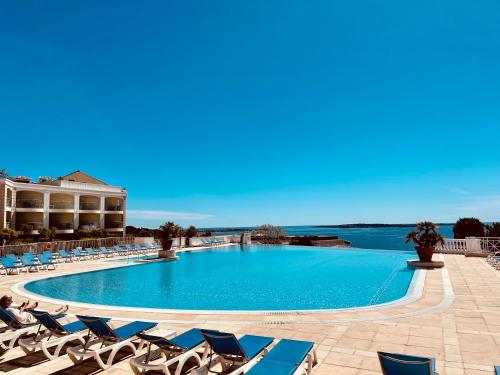 einen großen Pool mit Liegestühlen und einem Körper aus Wasser in der Unterkunft Cannes - Appartement rénové avec vue mer imprenable in Cannes
