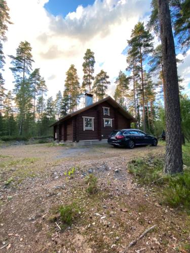 una cabaña en el bosque con un coche aparcado delante en Mökki järven rannalla mäntymetsässä en Forssa