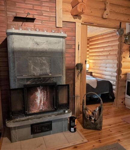 a living room with a fireplace in a log cabin at Mökki saunalla mäntymetsässä in Forssa