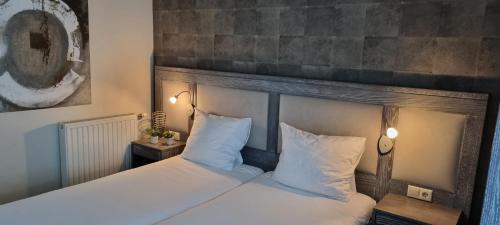 1 dormitorio con 1 cama con sábanas y almohadas blancas en Hotel Restaurant Keizersberg en Elsendorp