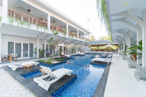 uma imagem de uma piscina do hotel com cadeiras e mesas em Sea Shell Resort em Gili Trawangan