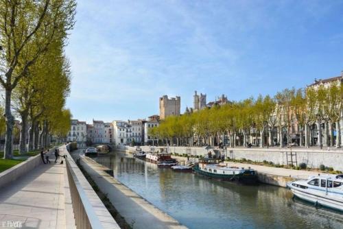 Un río en una ciudad con barcos dentro en Appartement Les Halles Narbonne, en Narbona