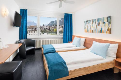 Habitación de hotel con cama y escritorio en Hotel Merkur - West Station en Interlaken