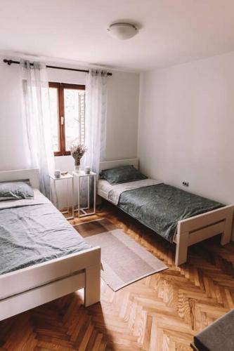 two beds in a room with wooden floors at Holiday house Zlata in Banjol