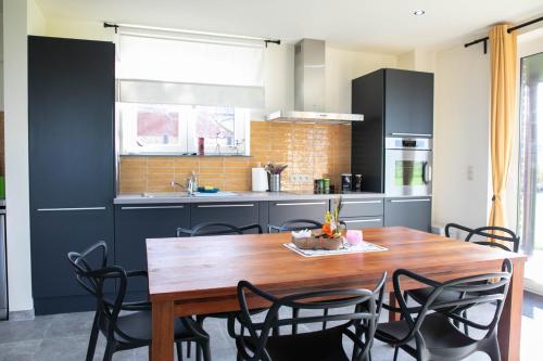 cocina con mesa de madera y armarios negros en Côté Jardin 