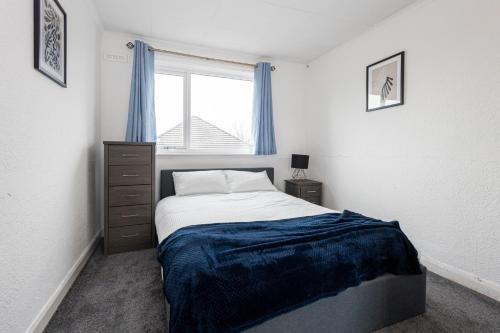 a bedroom with a bed and a window with blue curtains at M9 Guest House in Manchester