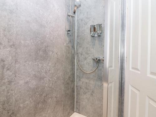 W łazience znajduje się prysznic ze szklanymi drzwiami. w obiekcie Steading Cottage w mieście Kirriemuir