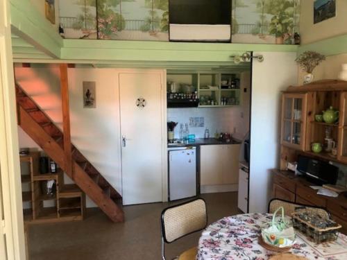 Zimmer mit einem Tisch und einer Küche mit einer Treppe in der Unterkunft CHALET avec PISCINE proche LAC et OCEAN in Carcans